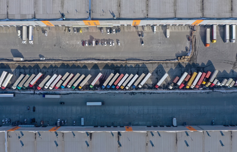Aerial view of a logistics center with numerous trucks lined up for loading and unloading deliveries.