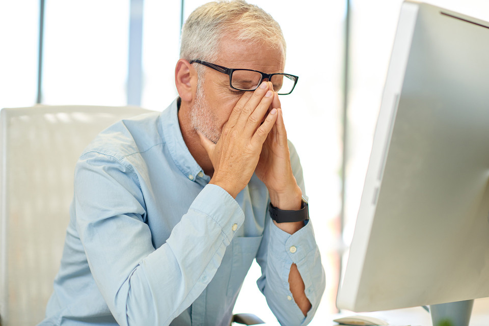 Businessman looking tired while working at his office desk