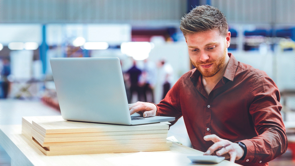 Man in production hall working on laptop