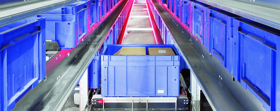 Automated storage system with blue bins and illuminated conveyor for efficient warehouse operations.