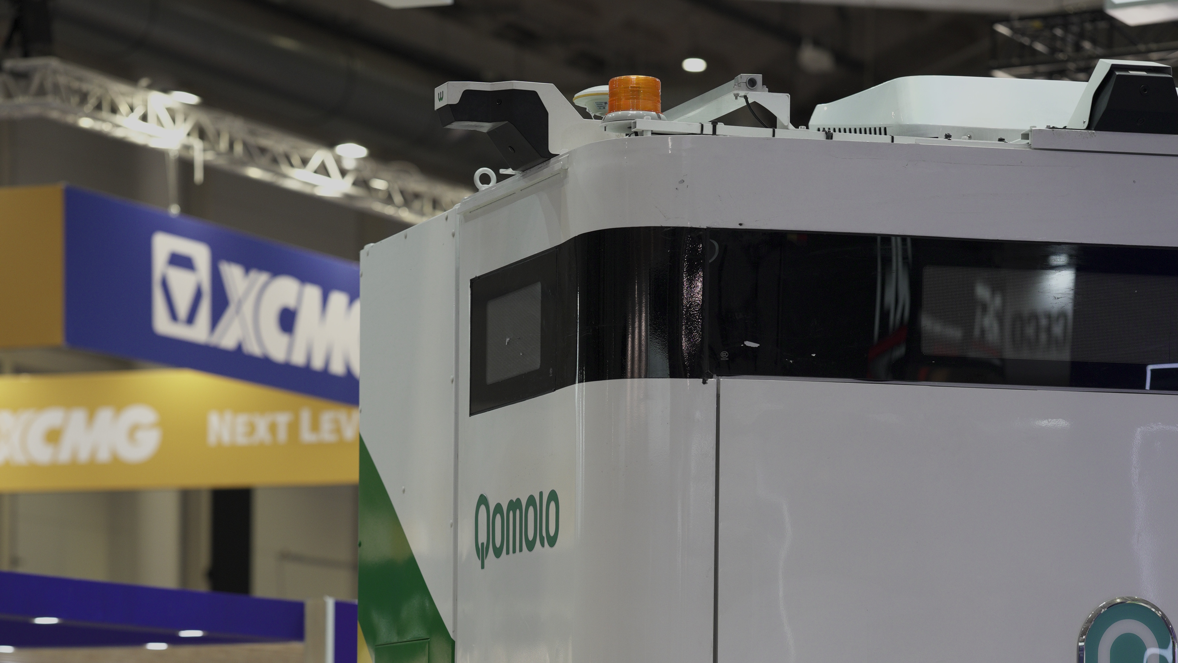 Qomolo electric vehicle display at industry expo, showcasing modern design and innovation in transportation.