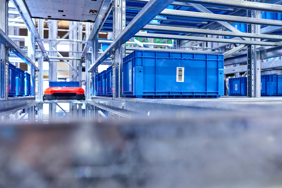 Worker in a warehouse handling a gray storage box, showcasing logistics and organization in inventory management.