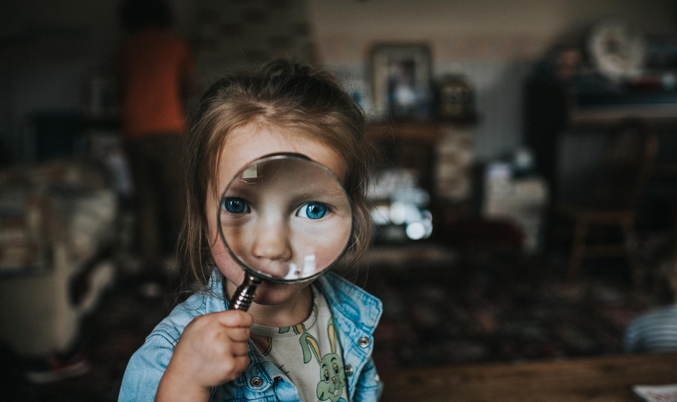 Image of child with magnifyer representing customer screening in KYC and CDD.