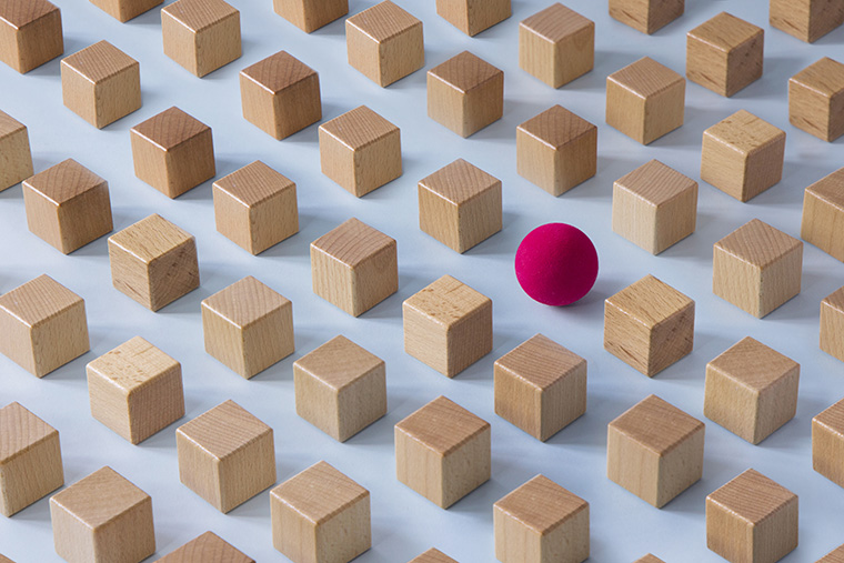 A grid of identical wooden cubes with one red sphere standing out, representing detection of anomalies & fraudulent claims