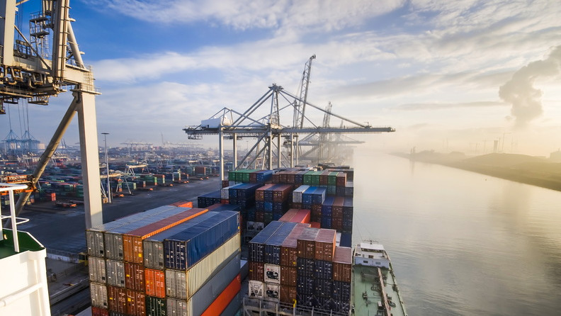 Blurred image of shipping containers with digital trading graph, symbolizing interconnection through data.