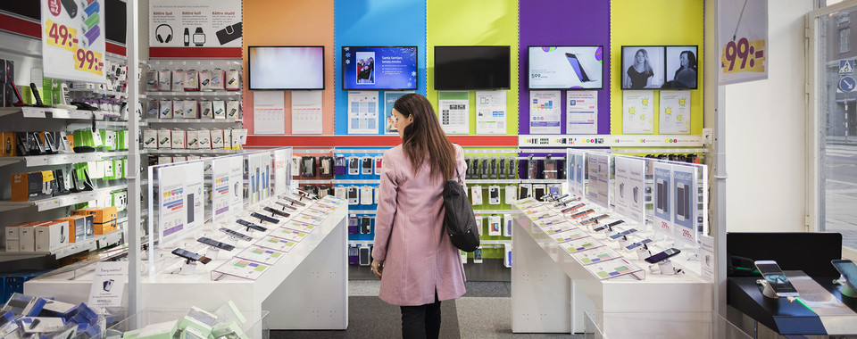 Woman in telecom store—subscription fraud risk during in-store onboarding and device sales.