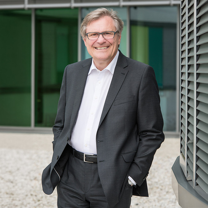 Smiling businessman in a suit stands confidently outside a modern building. Professional portrait for corporate use.
