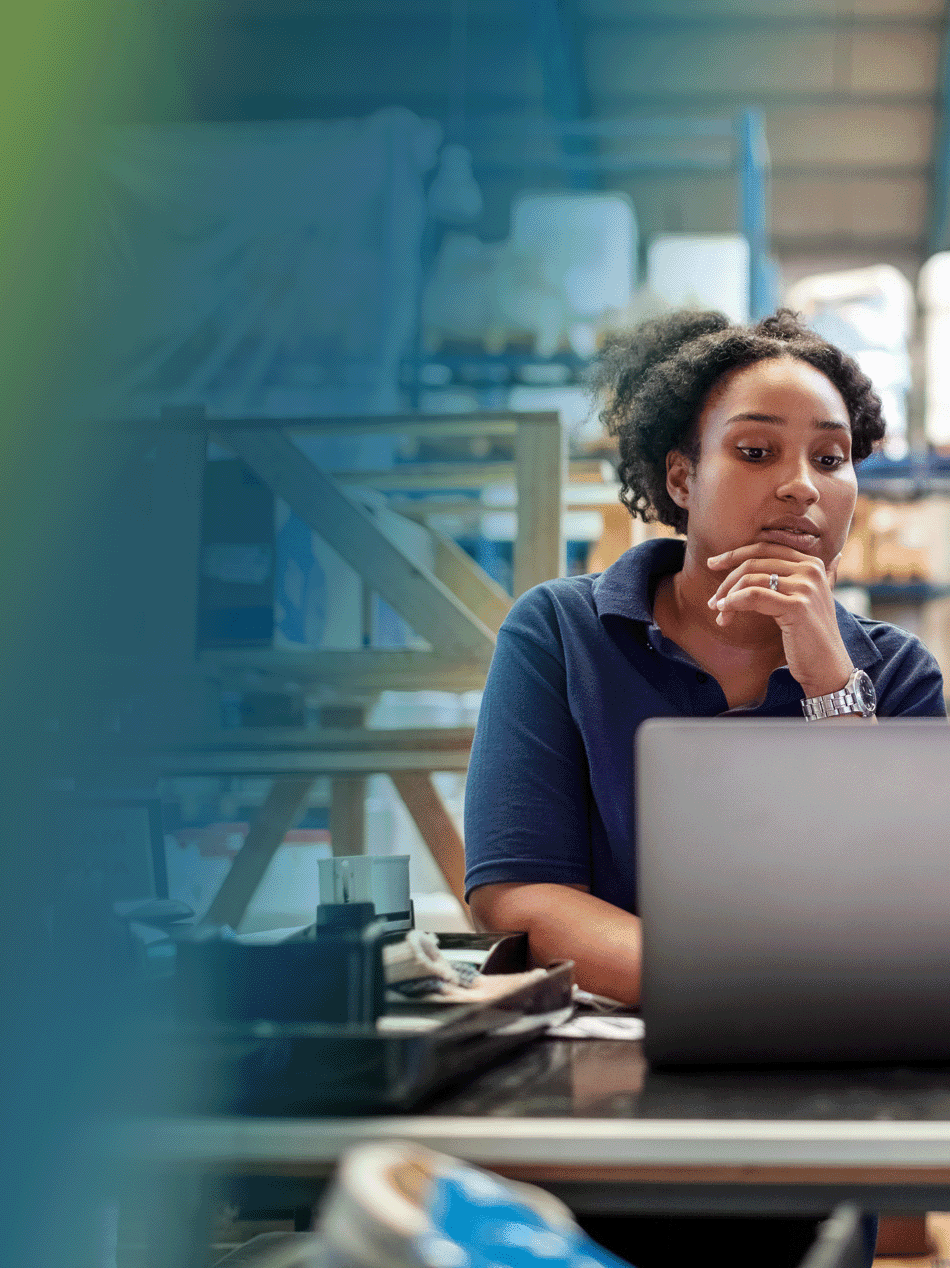 Zwei Frauen analysieren Daten am Laptop in einem Lager, um Geschäftsstrategien zu entwickeln.