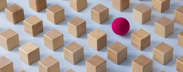 A grid of identical wooden cubes with one bright red sphere standing out among them, representing the detection of anomalies and fraudulent claims.