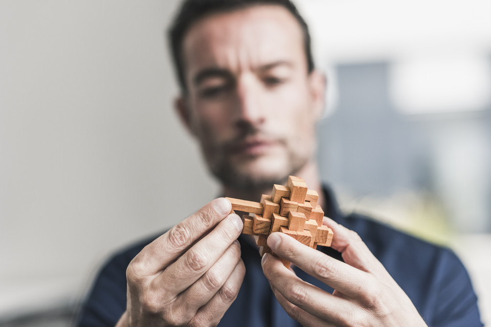 Man solving a wooden puzzle (GJKD Banks)