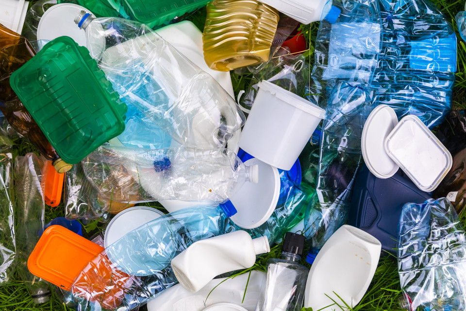 Verschiedene Plastikabfälle auf grünem Gras, die Recycling und Umweltschutz darstellen.
