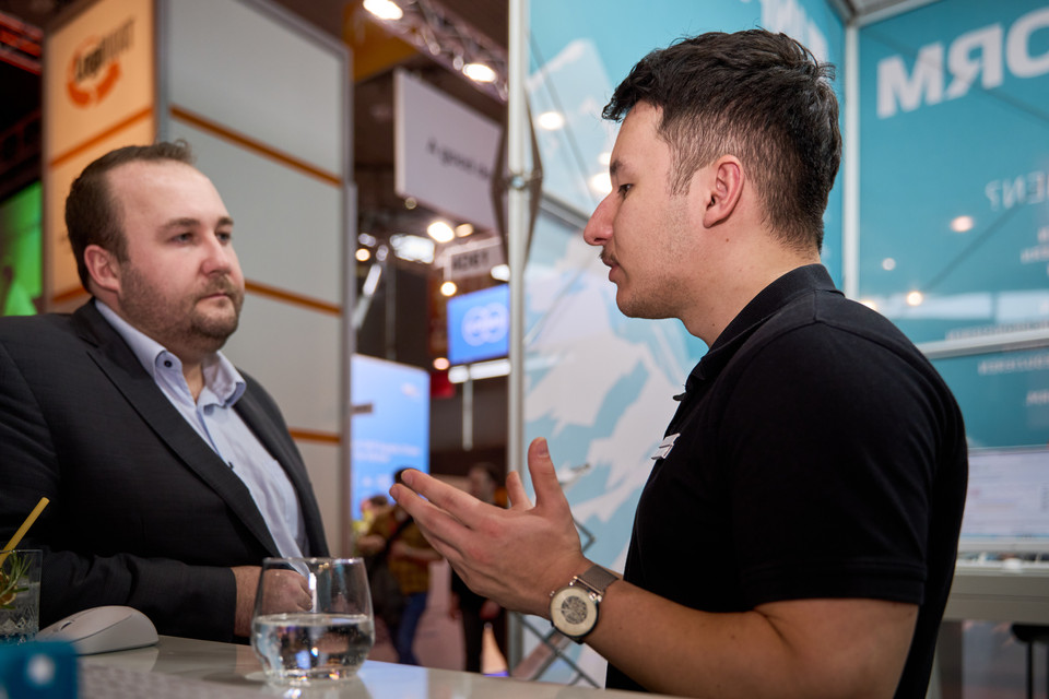 Gespräch zwischen zwei Menschen an einem Messestand, Fokus auf Interaktion und Engagement.