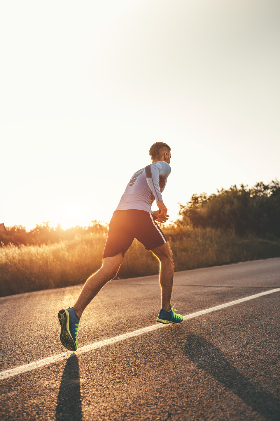 Runner training at sunrise on a quiet road, showcasing athleticism and dedication to fitness.