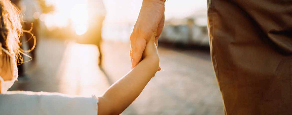 A parent and child holding hands at sunset, symbolizing love and connection in outdoor settings.