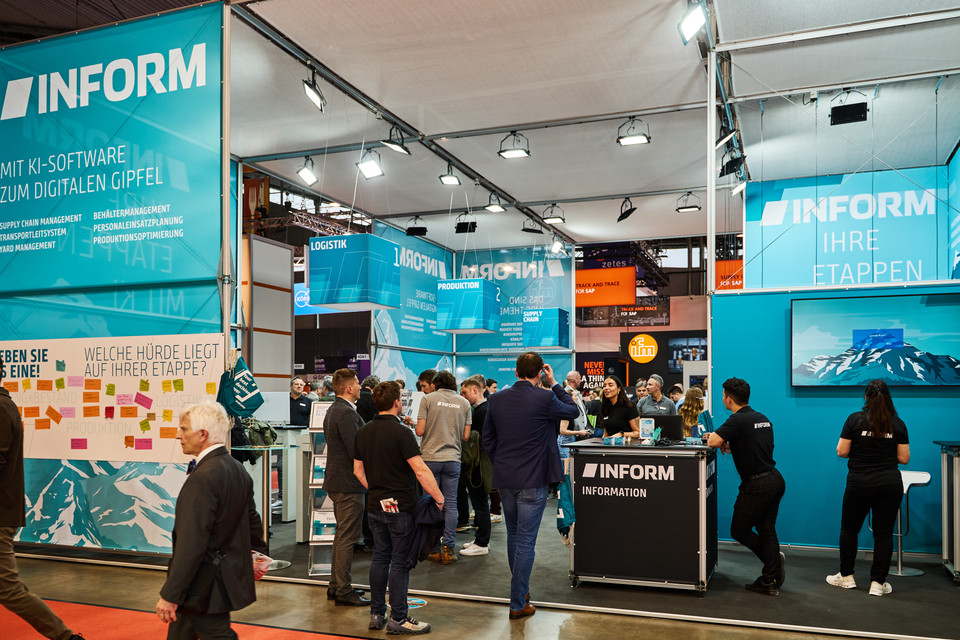 Messestand von INFORM auf einer Messe, Besucherinteraktionen und Präsentation von KI-Software für Logistik und Produktion.