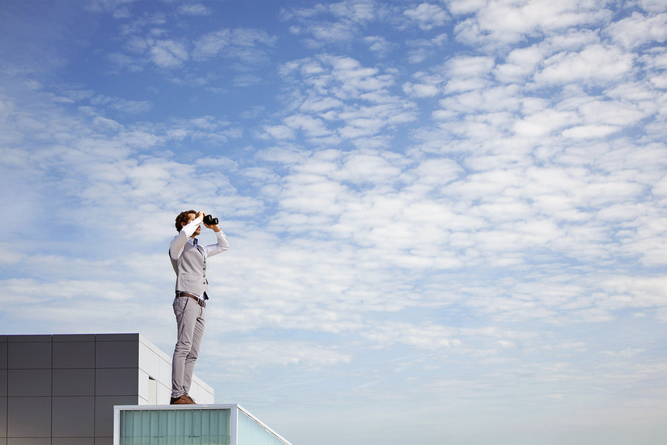 Business professional on a rooftop using binoculars, symbolising forward-looking PSD3 readiness in European payments