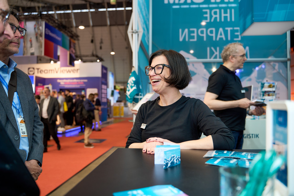 Besucher am Messestand mit Informationsmaterialien auf einem Event zur Logistikbranche in Deutschland.
