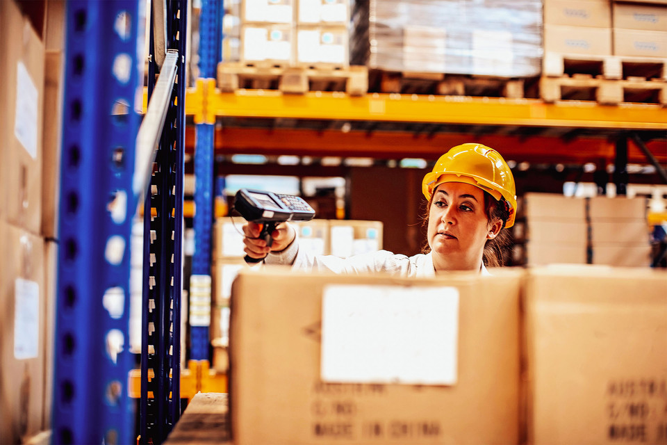 Arbeiter mit Scanner in einem Lager, um Pakete zu scannen und den Bestand zu verwalten.