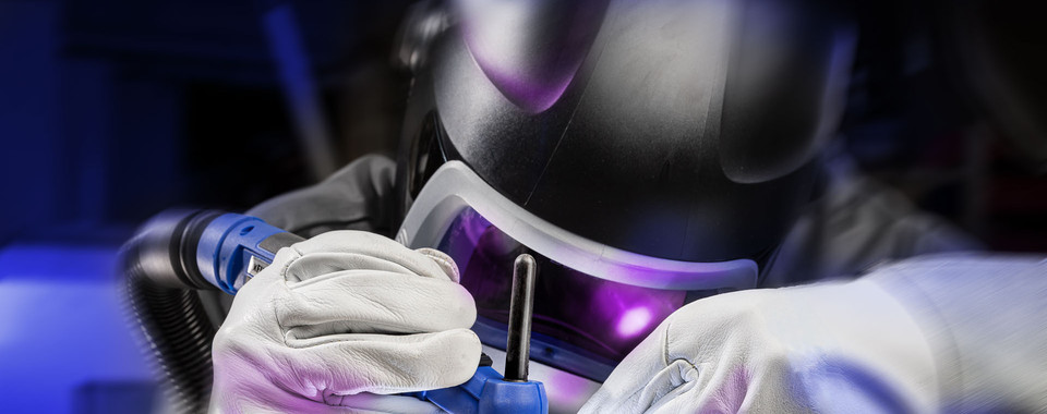 Schweißer mit Schutzausrüstung in Aktion, der Metall mit präziser Technik bearbeitet.